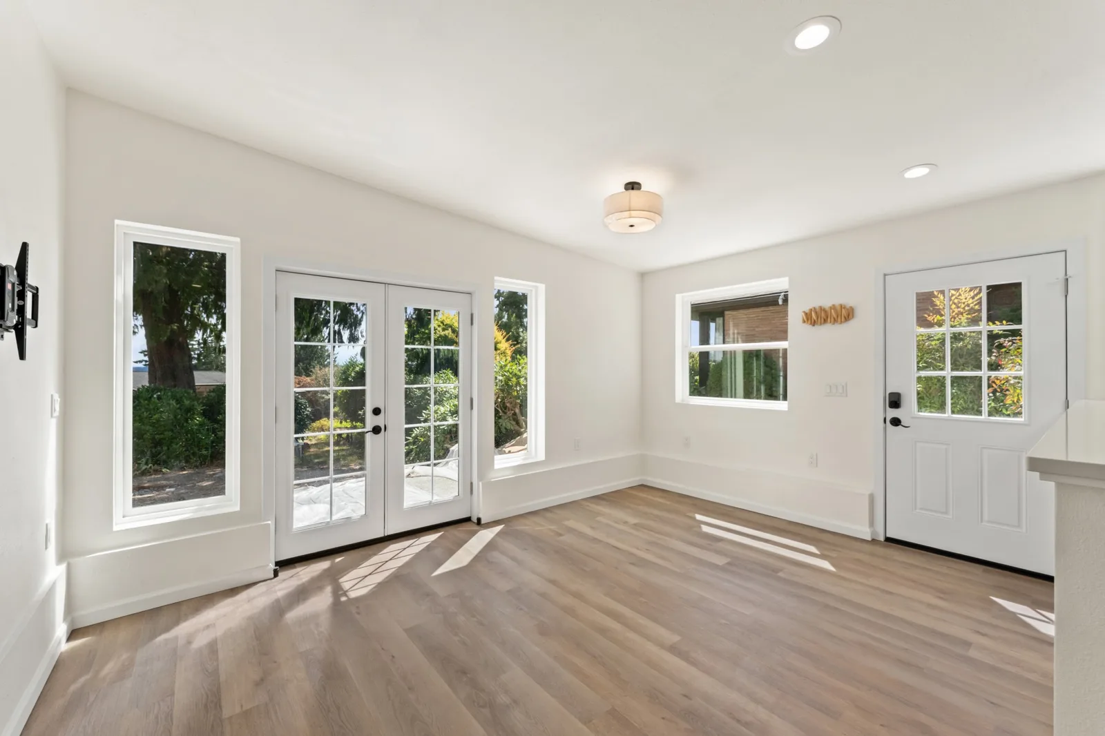 View Ridge ADU living room: French doors and two tall windows onto the private patio, oak floor in afternoon sun