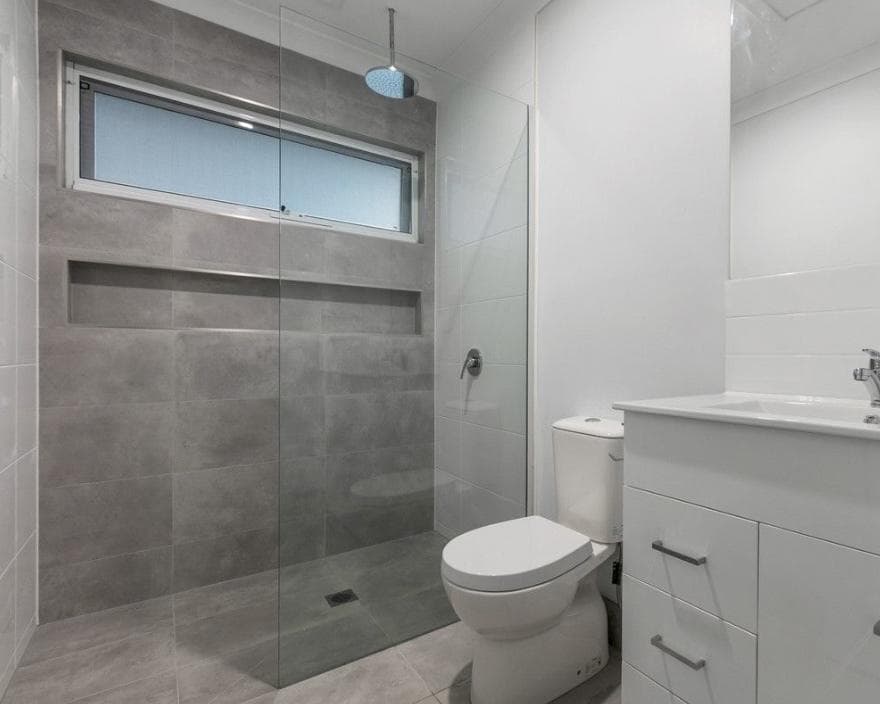 DADU bathroom Bothell — grey porcelain tile frameless shower ceiling rain head niche shelf