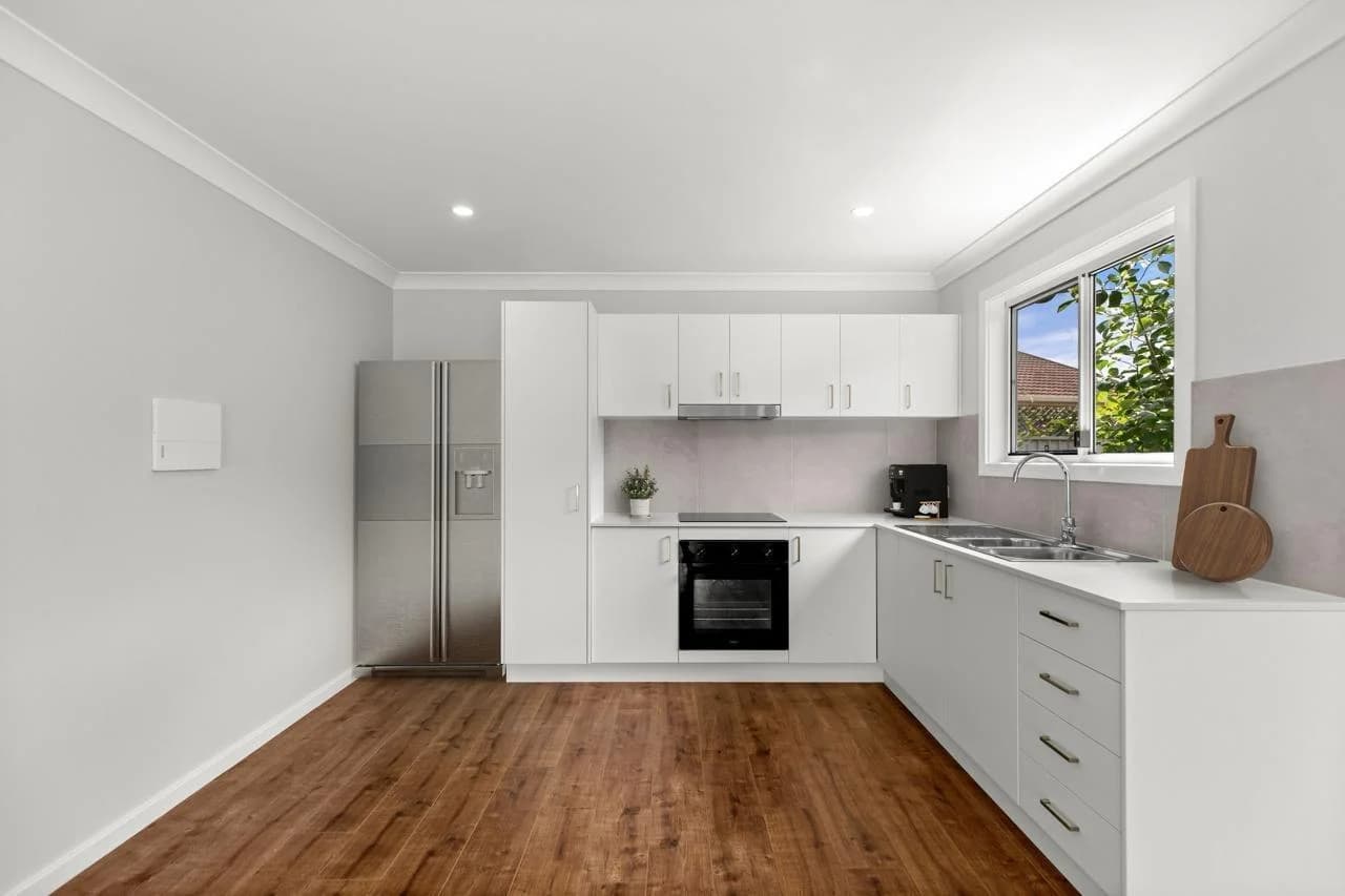 Rental DADU kitchen Bothell — white flat-panel cabinets quartz countertops LVP flooring stainless appliances