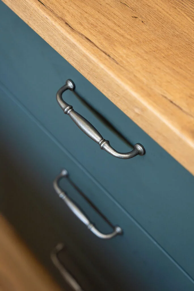 Antique pewter bail pull hardware on teal shaker cabinet with butcher block oak countertop — cottage kitchen Edmonds WA