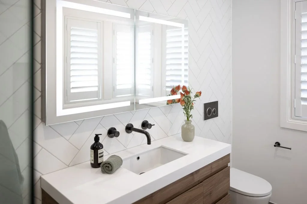 Walnut vanity with white quartz, matte black faucet, herringbone tile wall, LED mirror, and wall-hung toilet — Issaquah WA