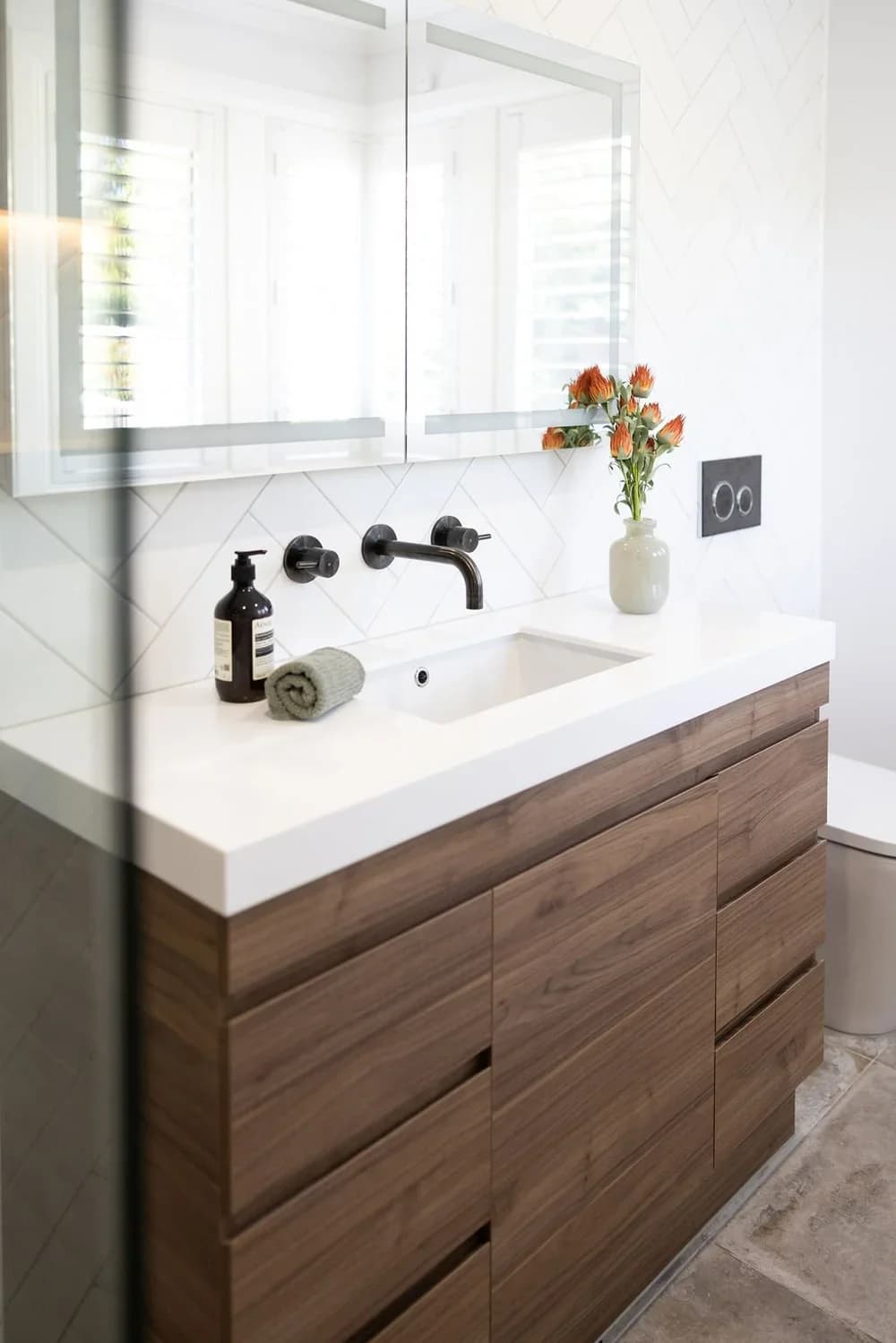Close-up of walnut floating vanity through frameless glass, white quartz top, matte black faucet — bathroom renovation Issaquah WA