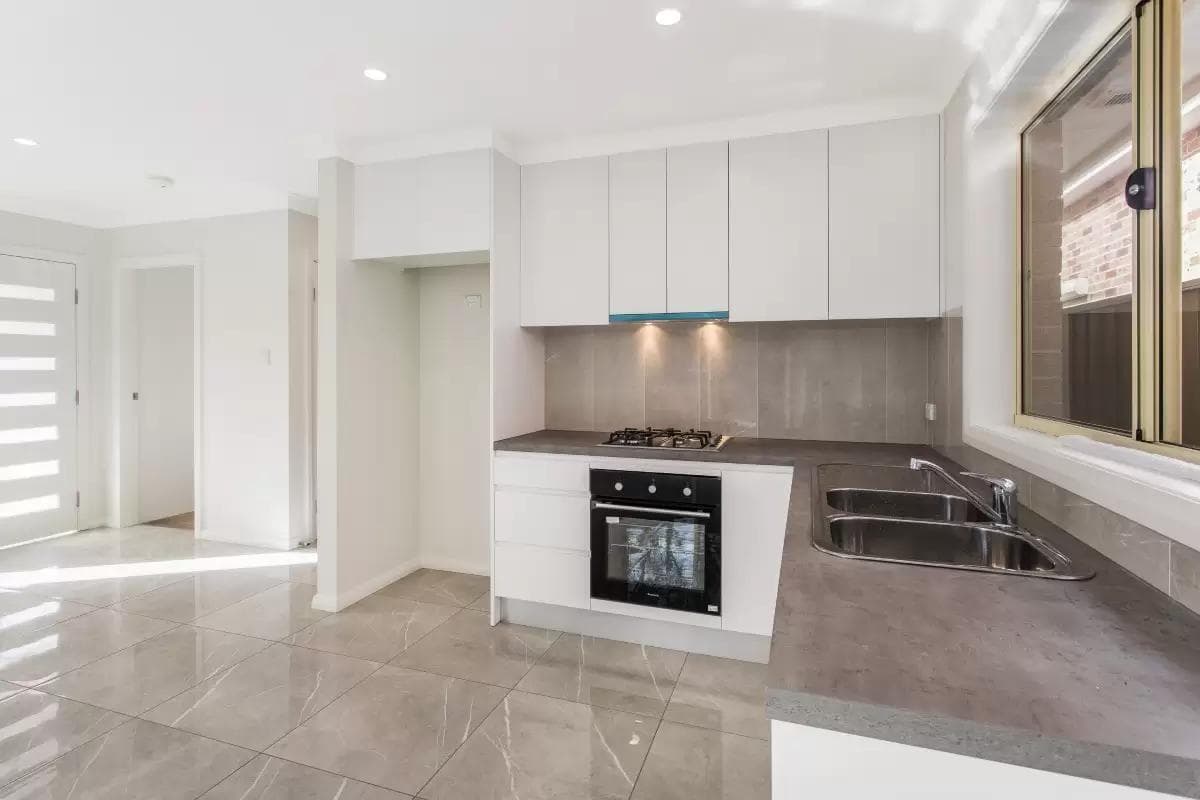 Premium ADU kitchen Kirkland — high-gloss cabinets polished porcelain tile gas cooktop