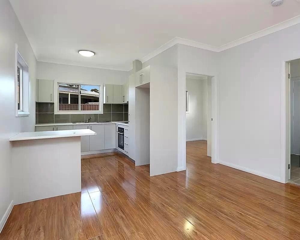 Open-plan kitchen living area detached ADU Renton — gray cabinets peninsula bar LVP flooring two bedrooms