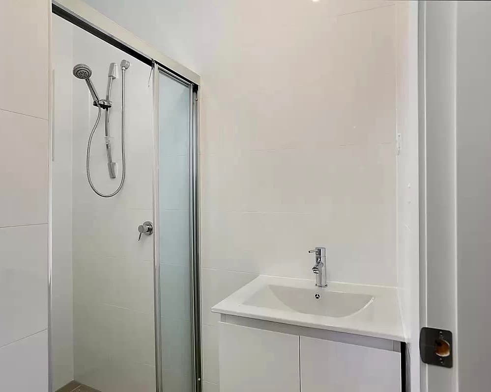 Bathroom shower backyard cottage Renton — sliding glass door white tile vanity chrome fixtures