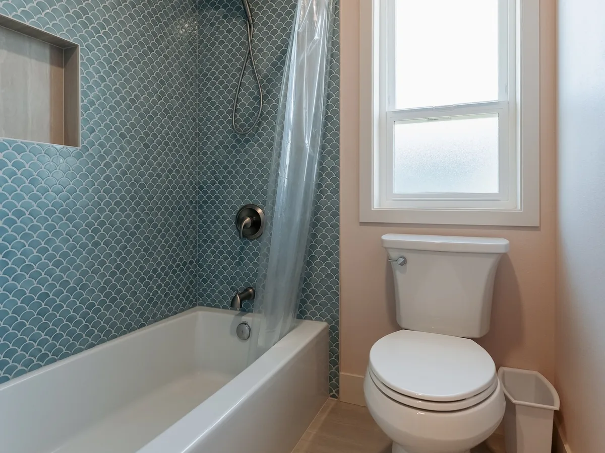 Tub with glazed blue fish-scale tile to the ceiling, a recessed niche and a window beside it, Capitol Hill Seattle