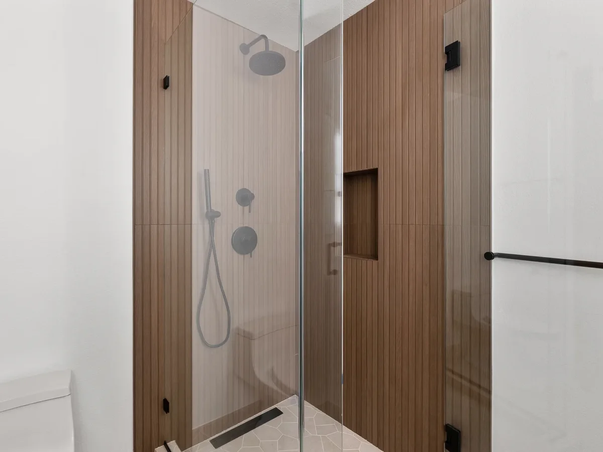 Wood-plank porcelain walk-in shower with glass panel and niche in a converted laundry room, Redmond WA