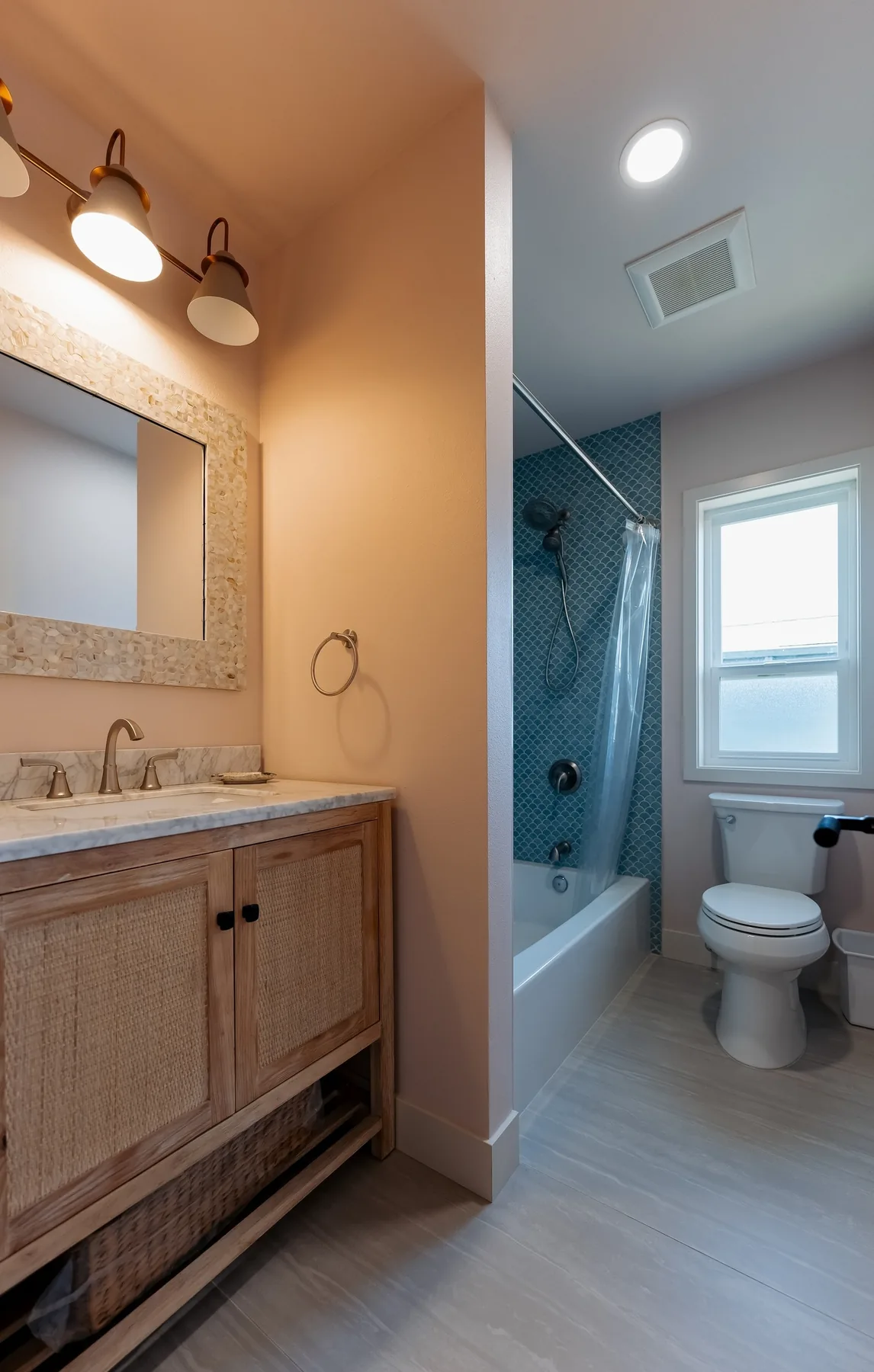 Light-oak vanity with marble top and shell-framed mirror, with the tub beyond, Capitol Hill bathroom
