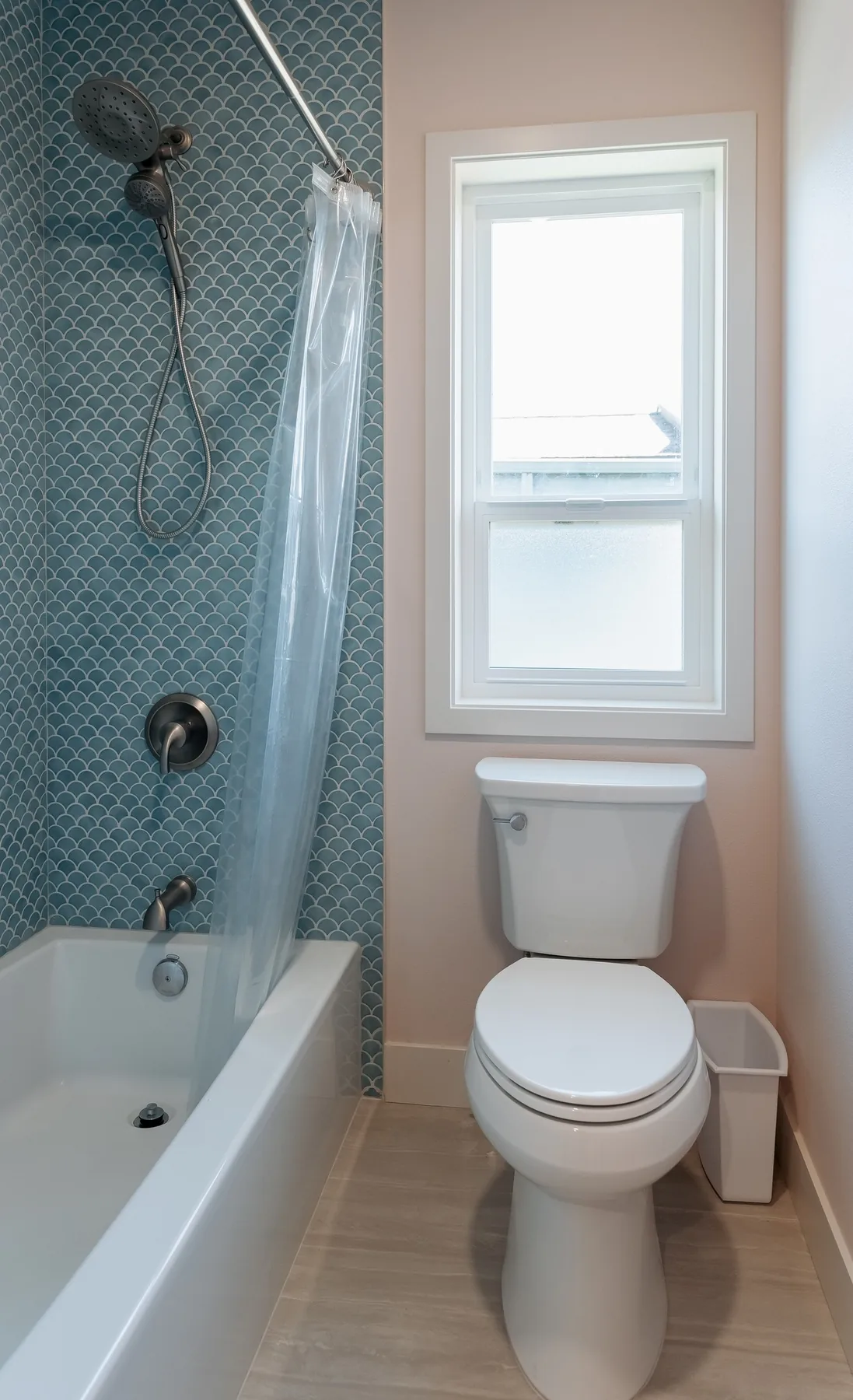 Tub-shower in blue fish-scale tile beside the toilet and window, Capitol Hill bathroom
