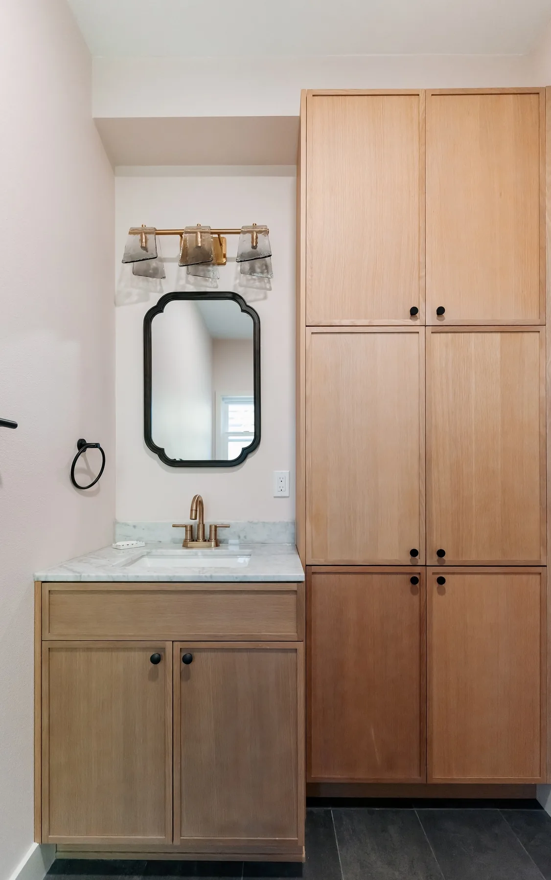 Oak vanity with marble top beside a tall oak linen cabinet, Capitol Hill bathroom