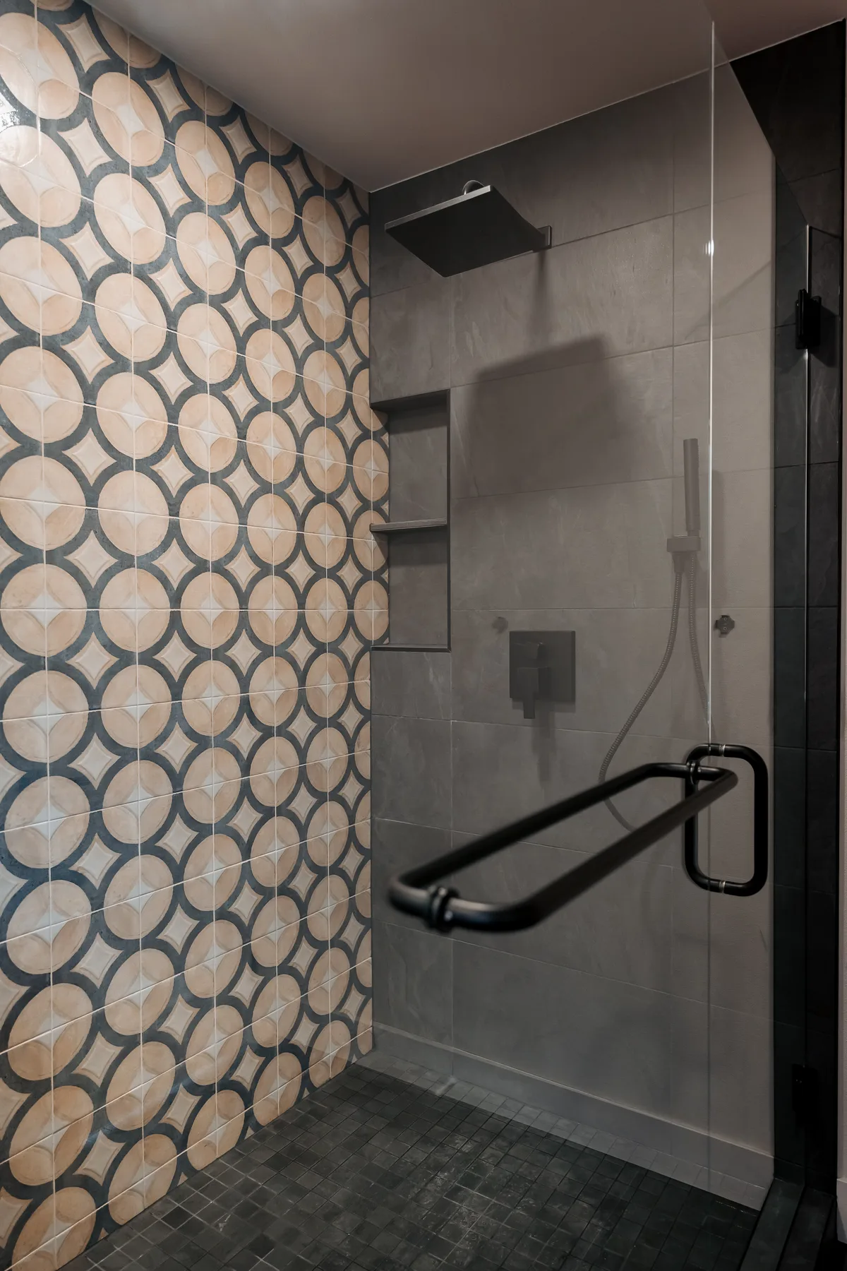 Patterned porcelain shower wall with recessed niche and matte-black grab bar