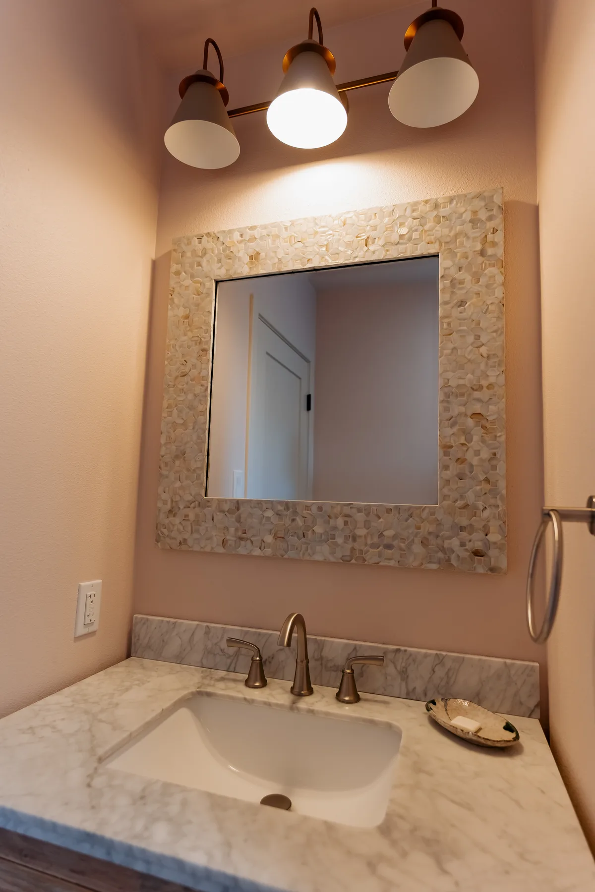 Marble vanity top with brushed-nickel faucet and a shell-framed mirror
