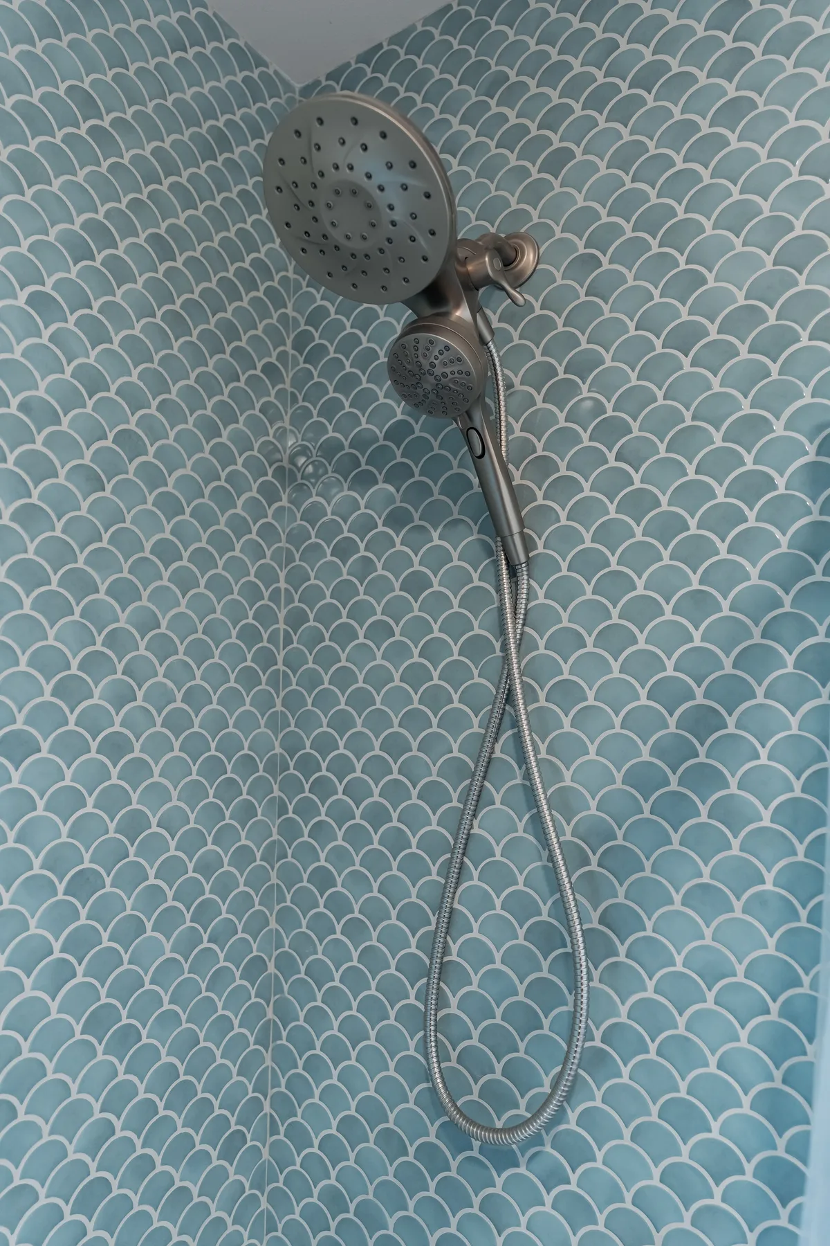 Blue fish-scale tile with a brushed-nickel handheld shower head