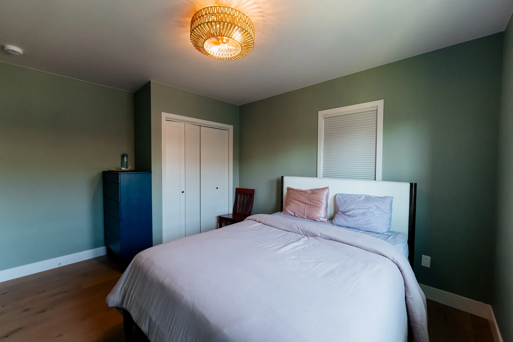 Bedroom with deep green walls, new closet doors and a rattan ceiling light, Capitol Hill remodel