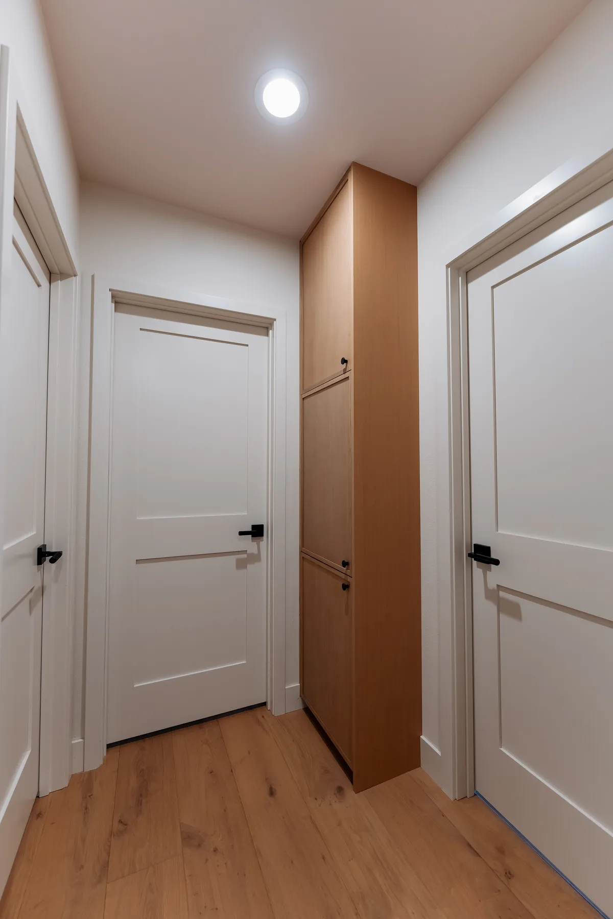 New white five-panel interior doors with black hardware and oak flooring