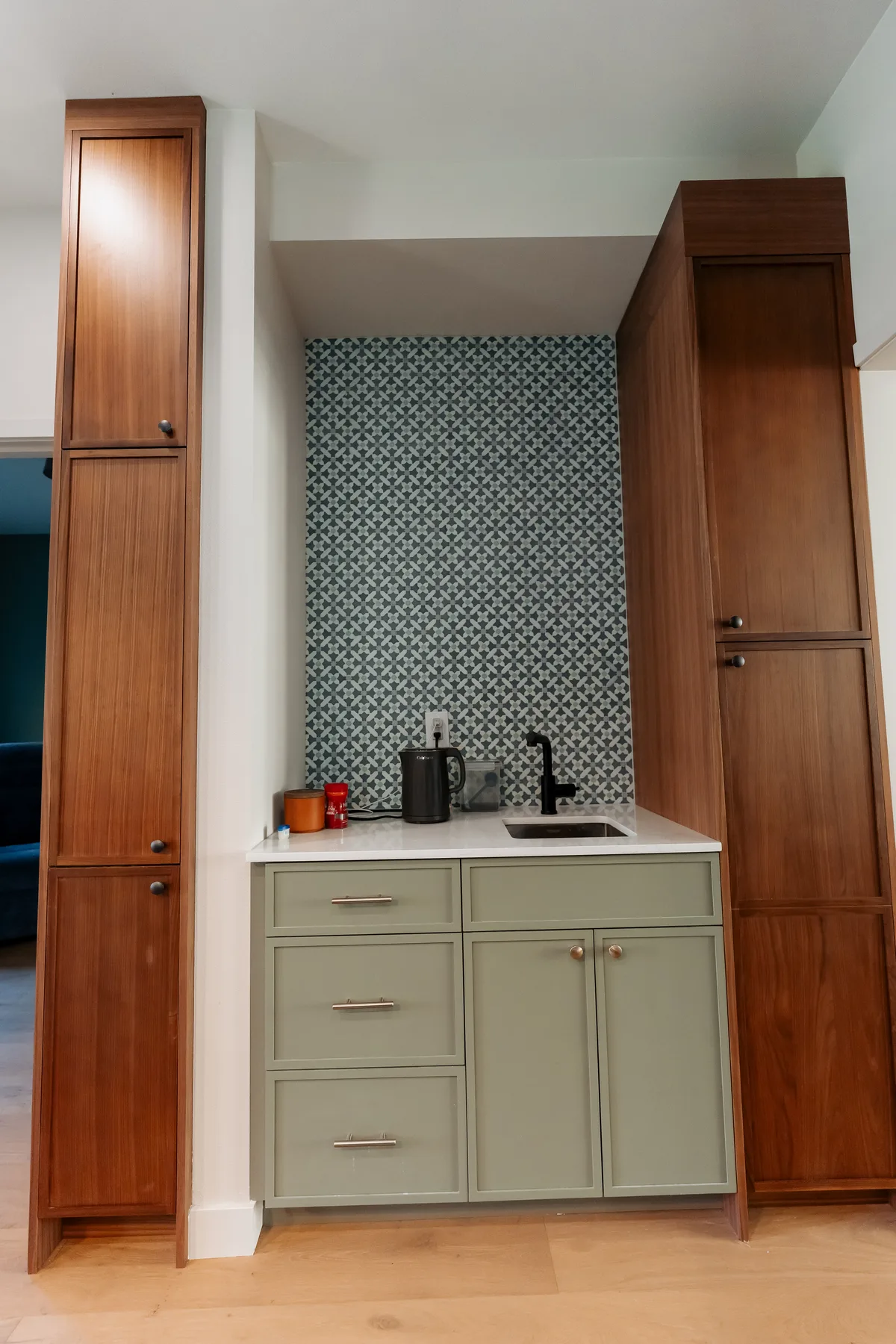 Coffee bar with a small sink between tall walnut pantry cabinets