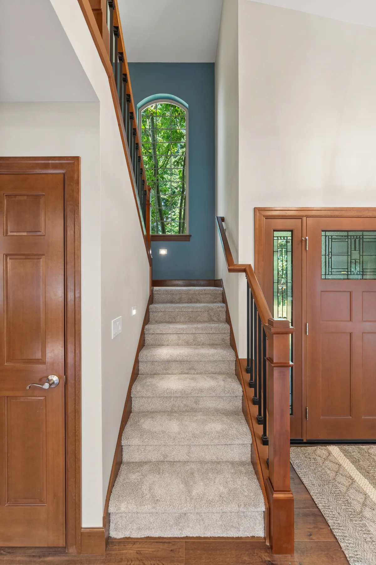 Staircase with blue accent wall, arched window and solid-wood door in Puyallup, WA