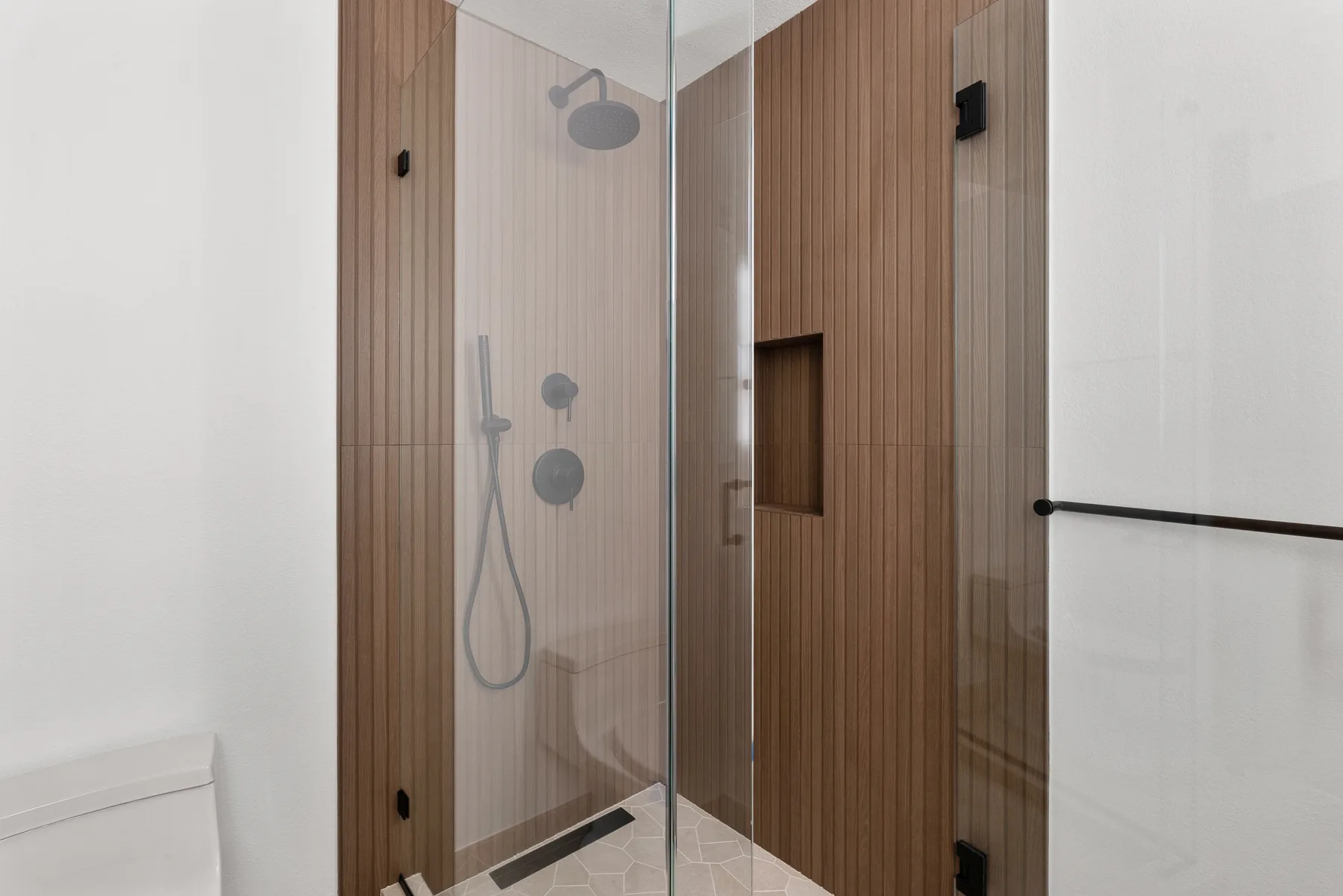 Wood-plank porcelain walk-in shower with glass panel and niche in a converted laundry room, Redmond WA