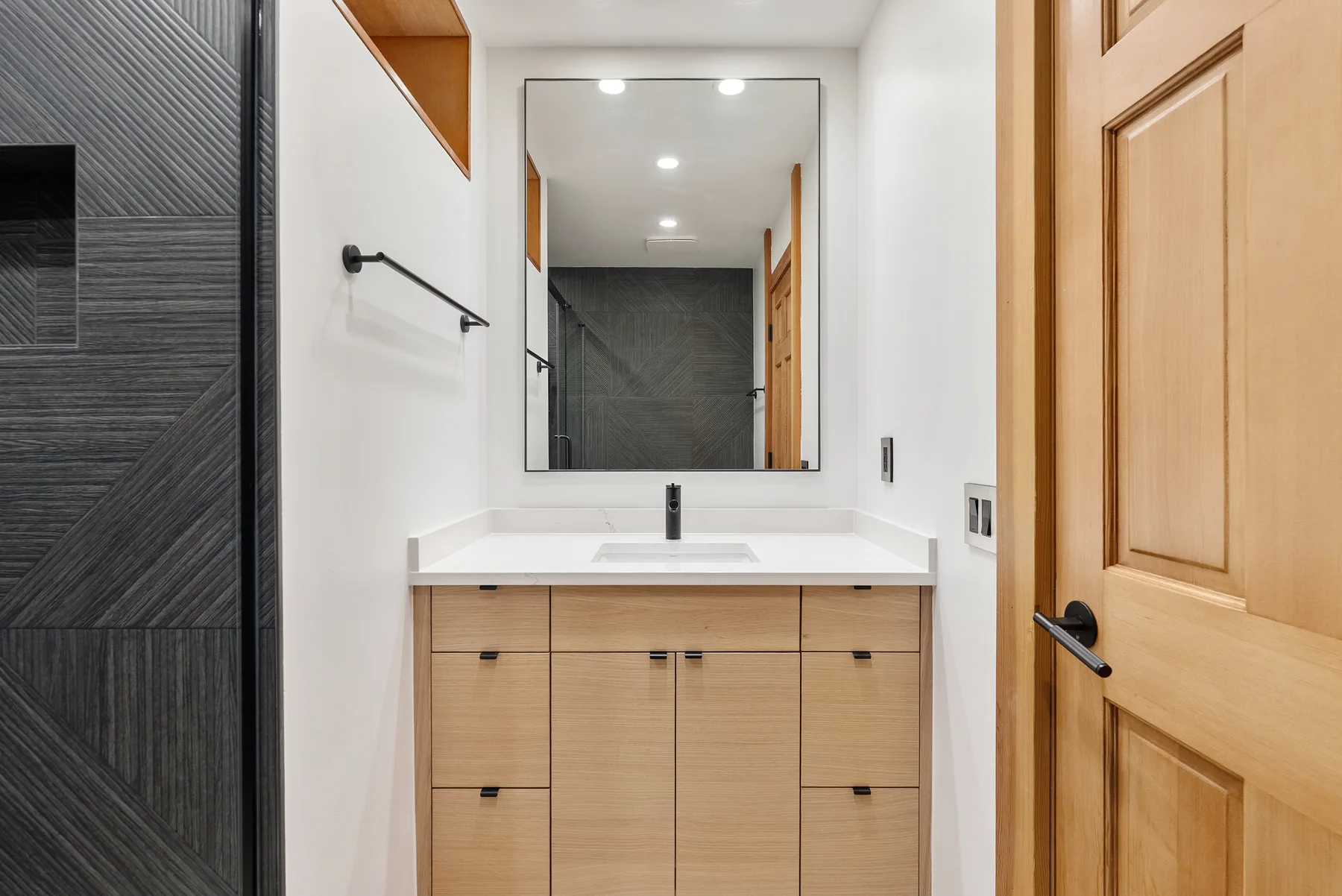 Finished main bathroom with charcoal tile walk-in shower and oak vanity in Redmond, WA