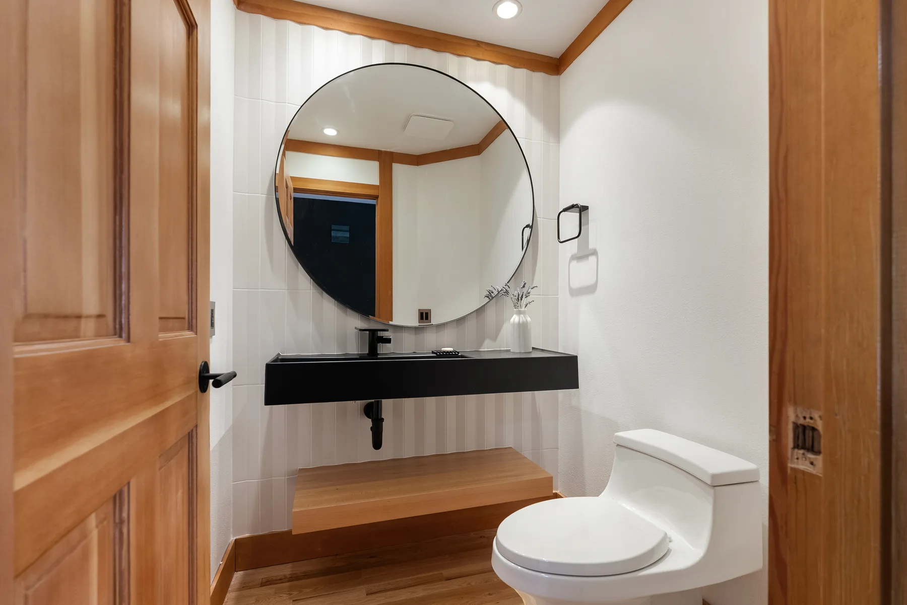 Powder room with floating black vanity, round mirror and fluted tile, Redmond WA