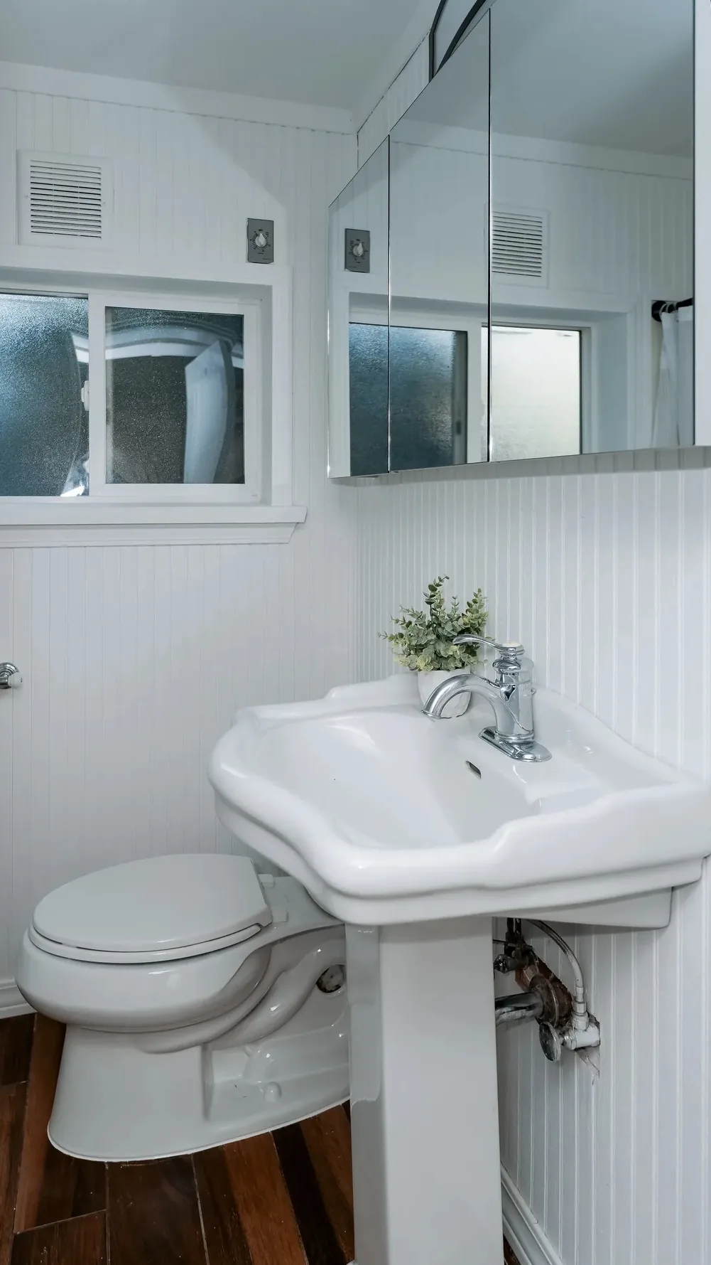Half bath with pedestal sink and white beadboard in the same Sand Point home