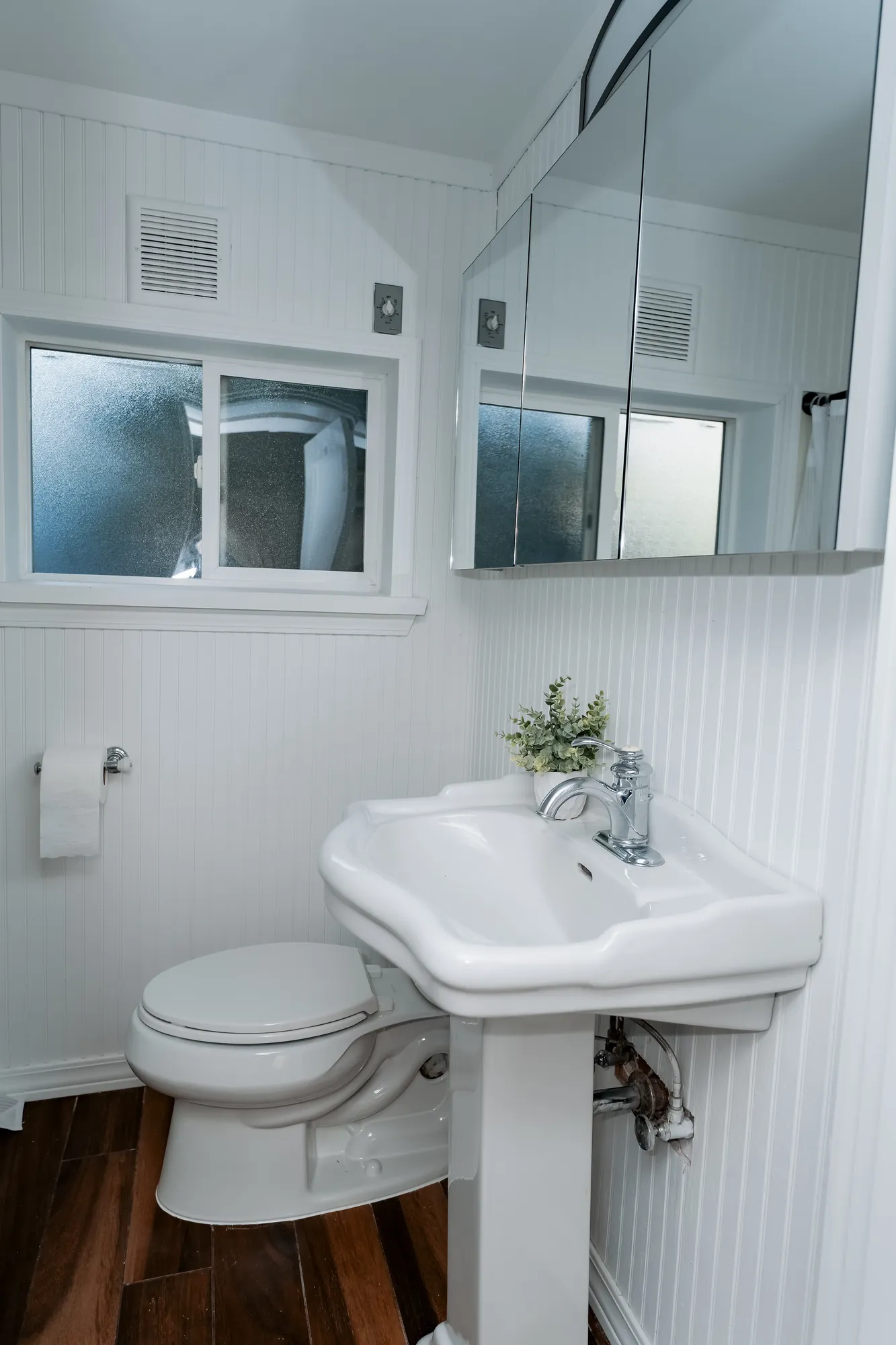 Refreshed powder room with pedestal sink and beadboard