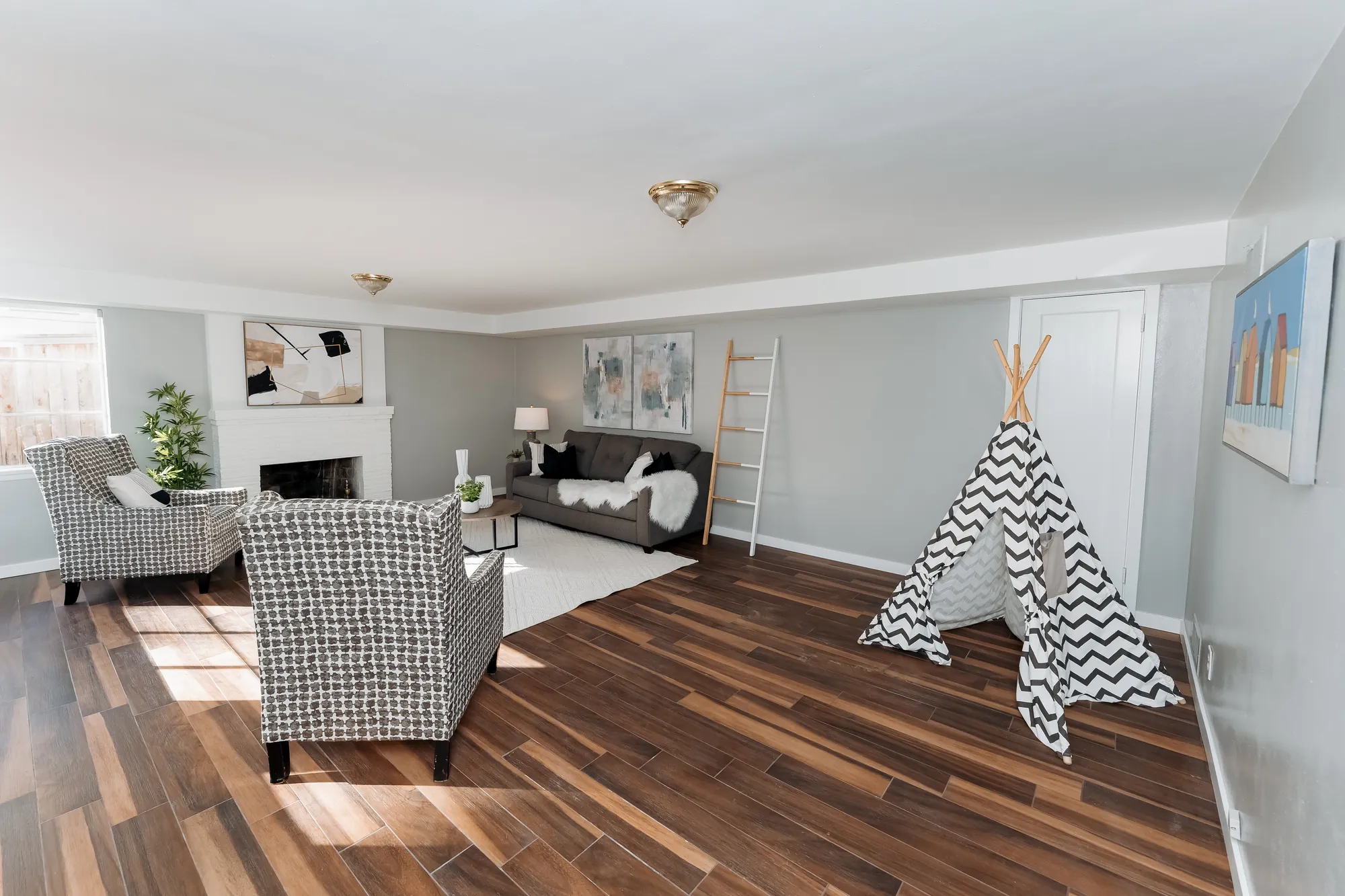 Lower-level family room with walnut-toned floors after restoration