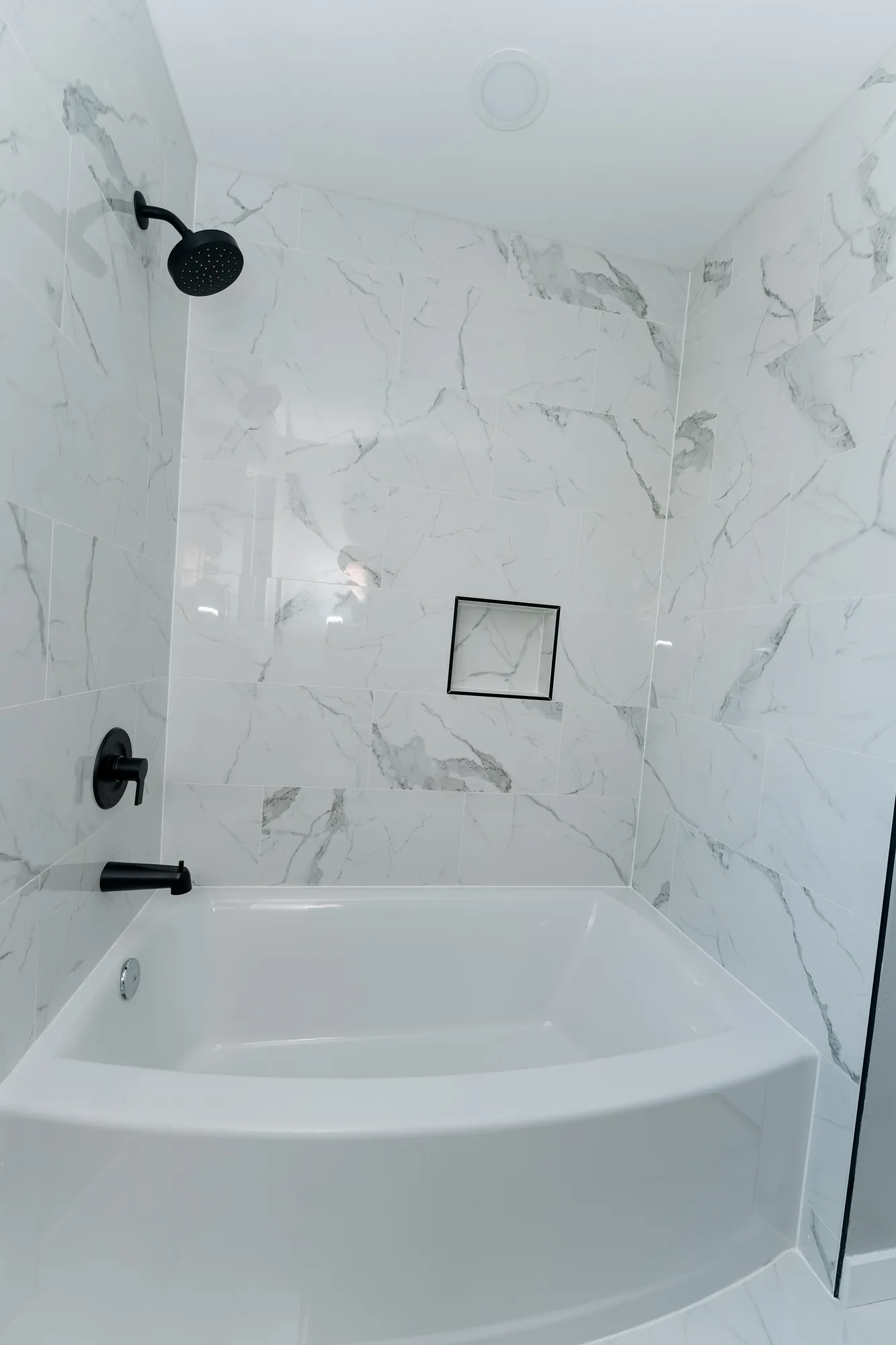 New bathroom marble-look shower and tub with matte-black fixtures