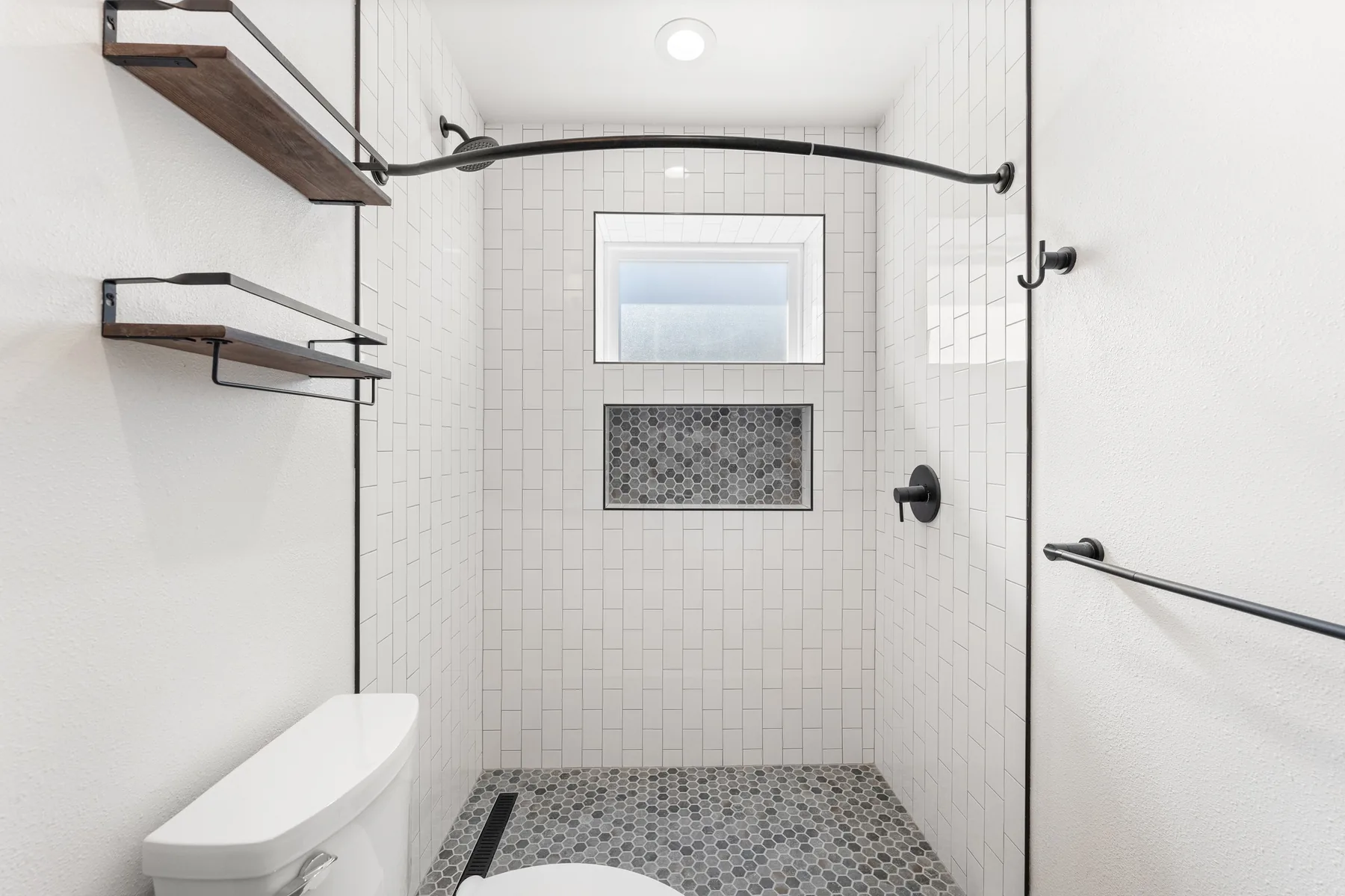 Walk-in white subway tile shower with hex-mosaic niche under a window, View Ridge ADU